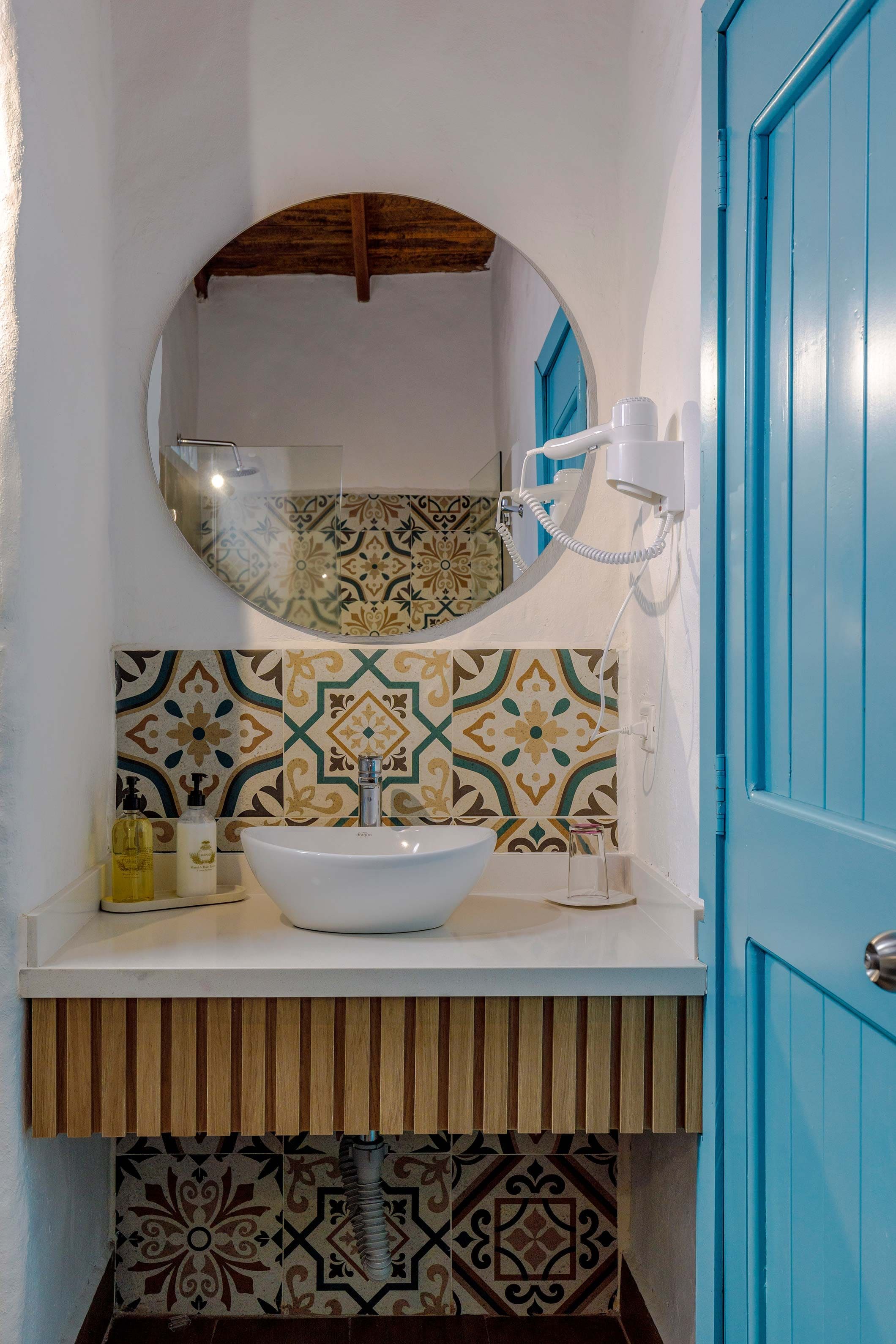 A bathroom with a white sink, a mirror, and patterned tiles.