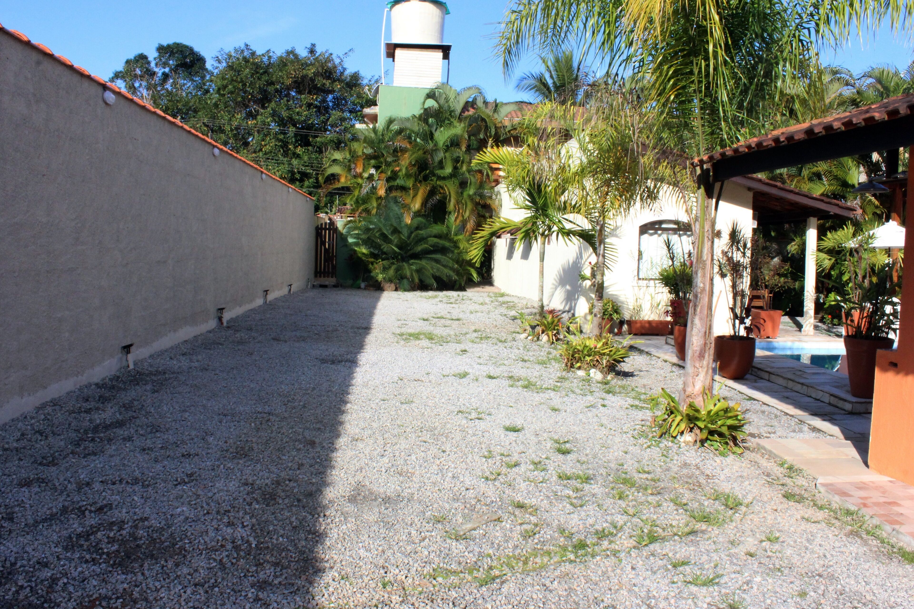 A courtyard with a gravel ground, a white wall, and a green structure in the background.