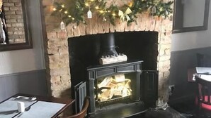 A cozy room with a fireplace, a clock, and a table with chairs. - The Oddfellows Arms (Leeds)