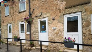 A stone building with three white doors, each with a small window above. There are flower pots on the steps and a sign that says "The Inn." - The Oddfellows Arms (Leeds)