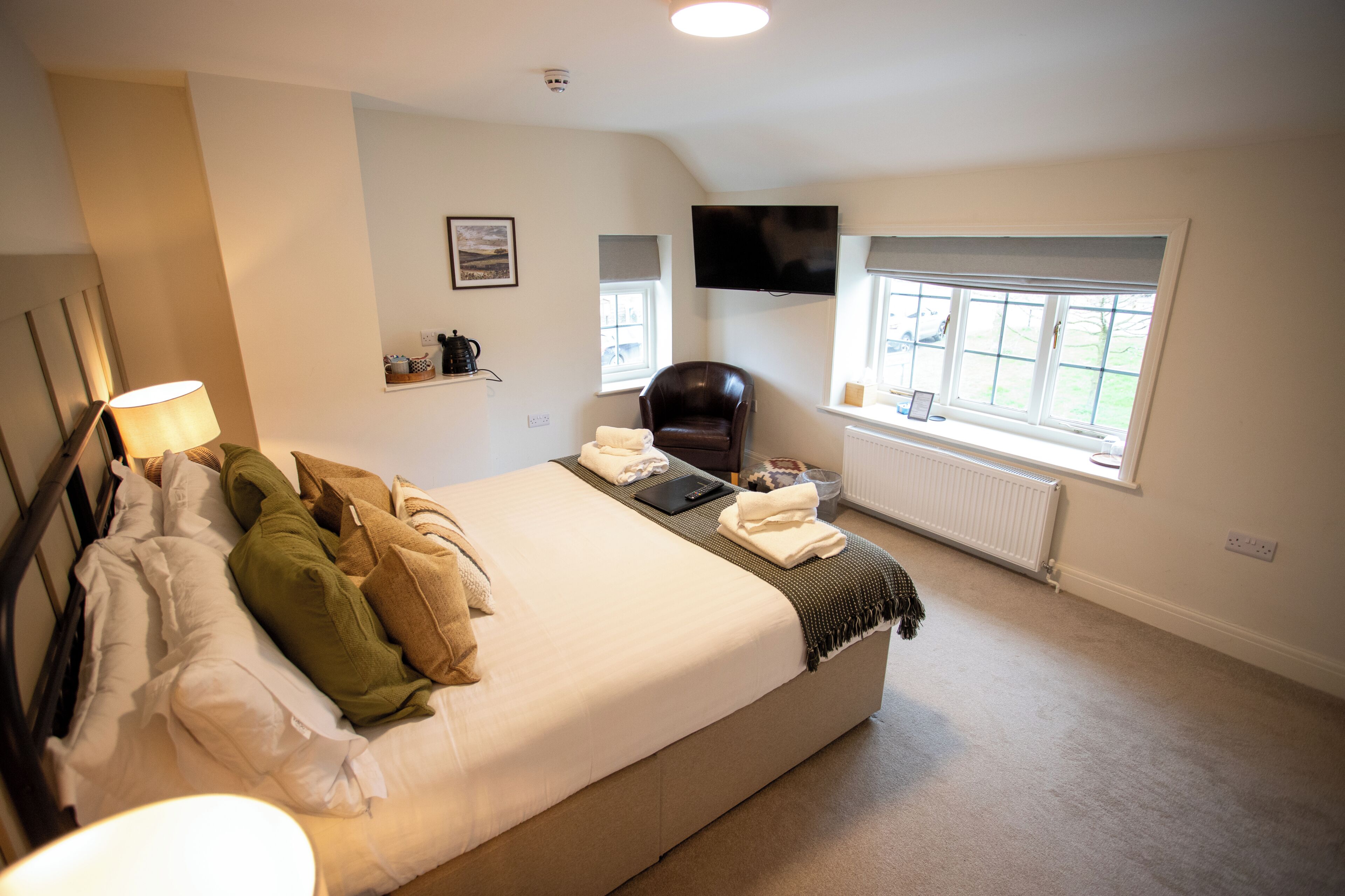 A bedroom with a bed, a chair, a television, and a window.