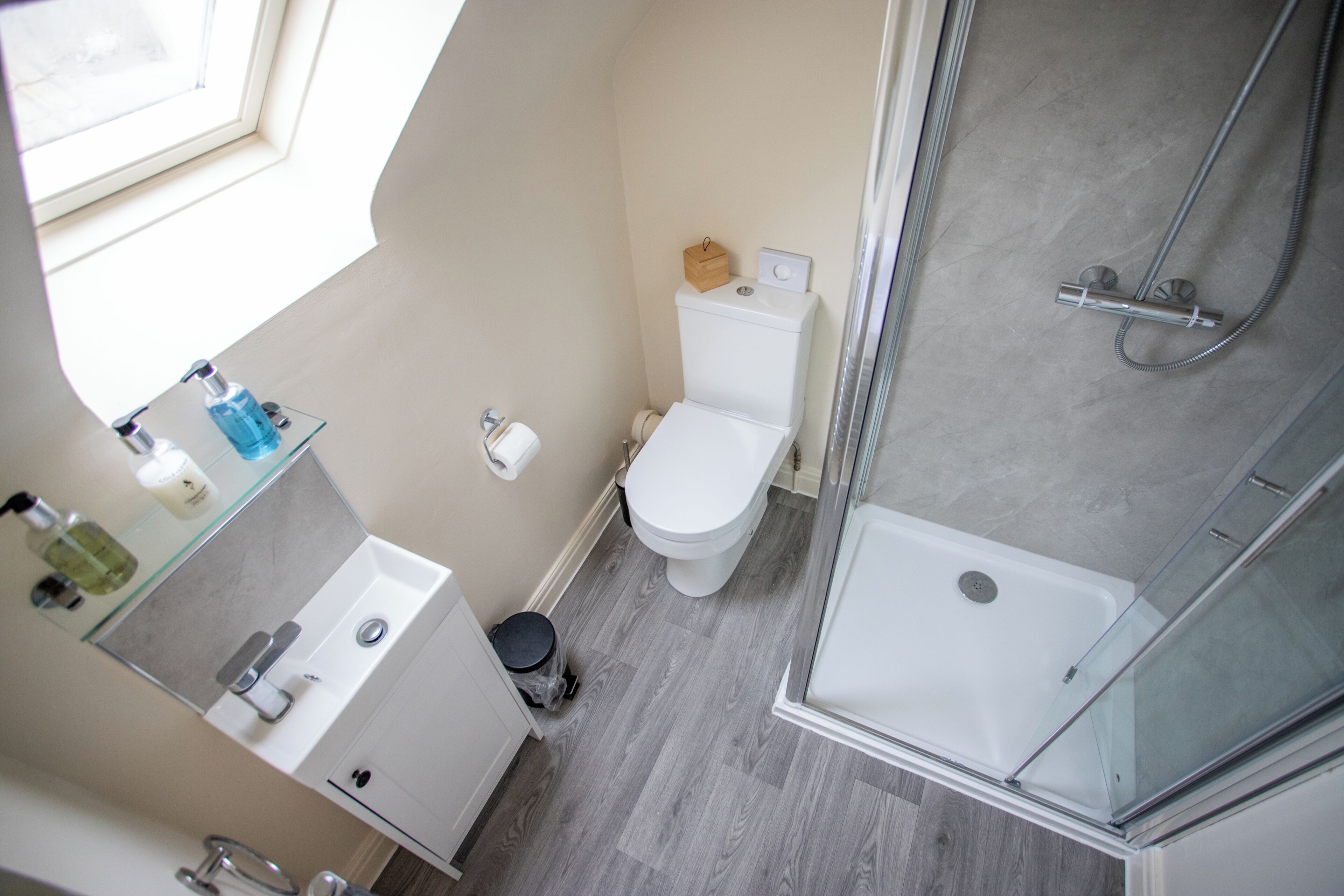 A modern bathroom with a glass shower enclosure, a toilet, and a sink with a mirror.