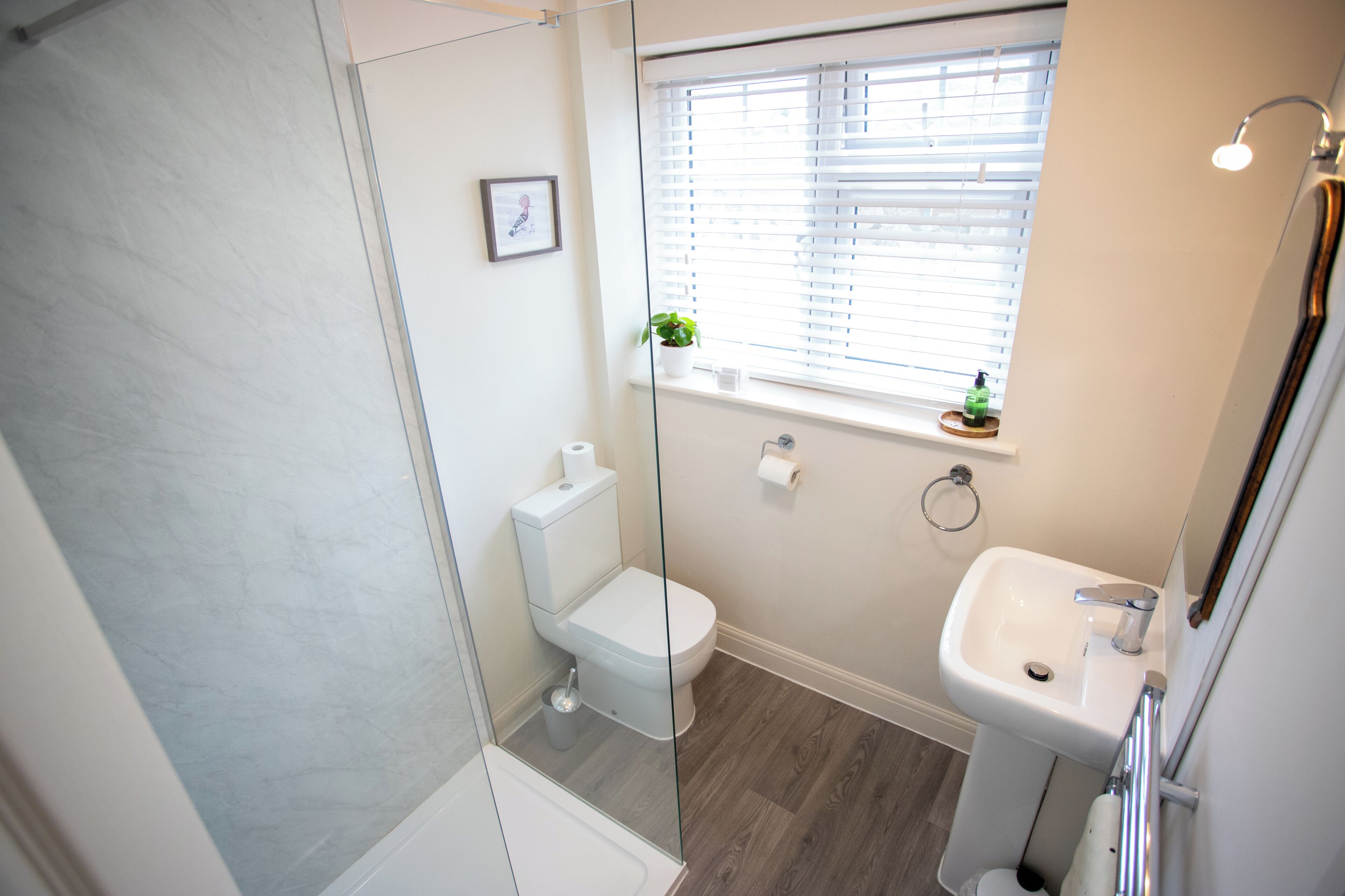 A bathroom with a toilet, sink, and shower.