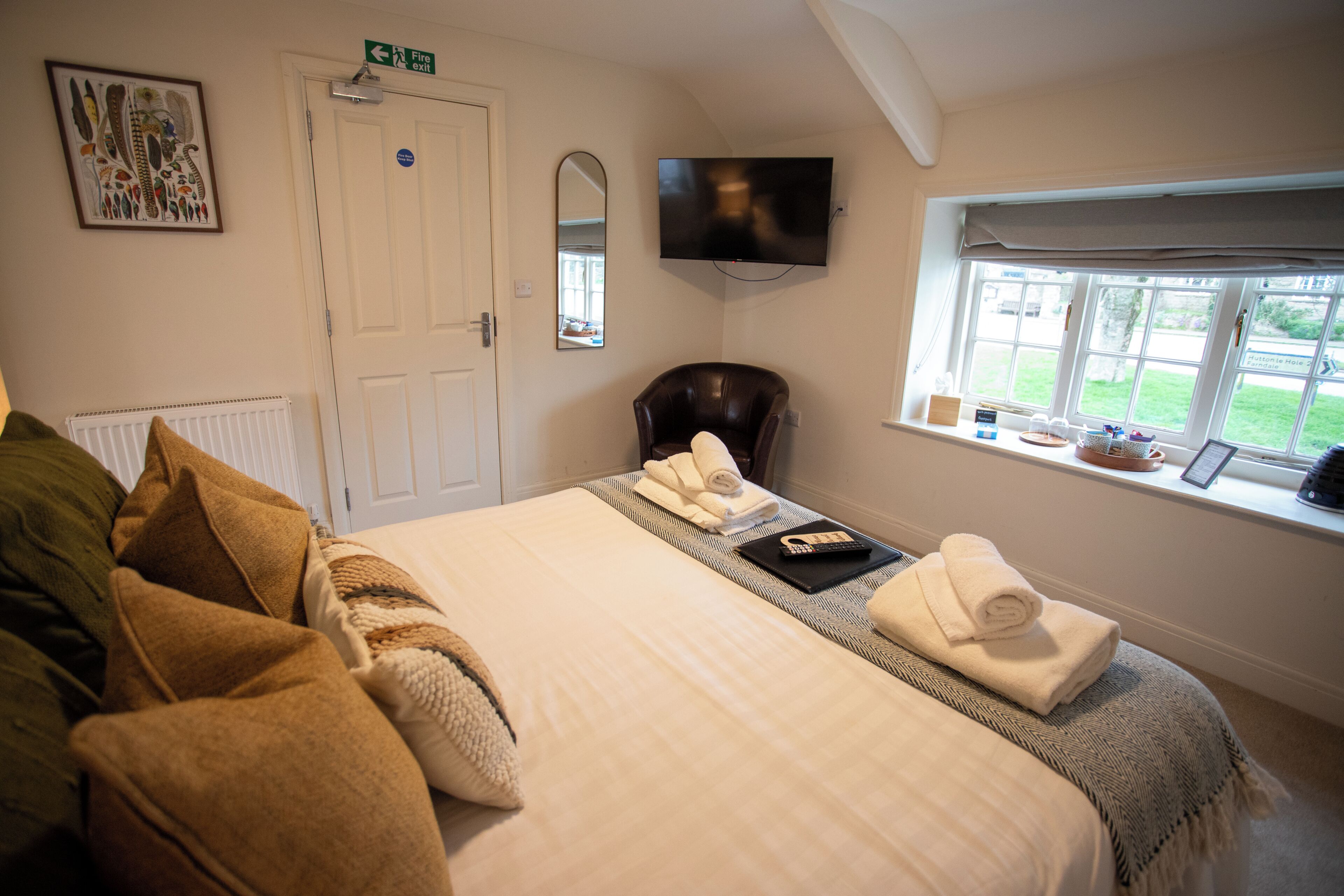 A hotel room with a bed, a chair, a TV, and a window with a view.