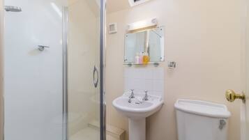 A bathroom with a glass shower enclosure, a pedestal sink, and a toilet.