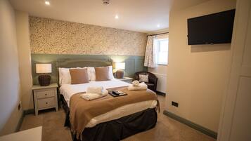 Habitación de hotel con cama, mesitas de noche, lámpara, silla, televisor y ventana con cortinas.