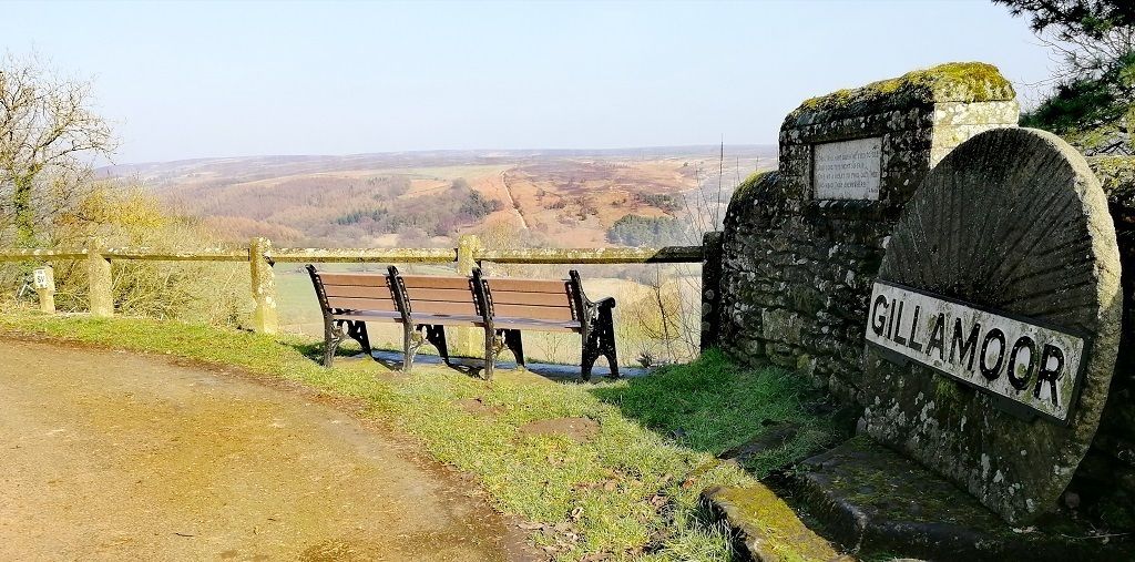 A bench area with a stone sign reading "GILLAMOOR" and a view of the countryside.