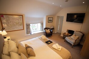 A hotel room with a large bed, a TV, a map on the wall, and a window with curtains. - The Royal Oak Inn (York)