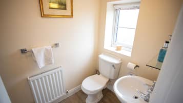 Ein Badezimmer mit Toilette, Waschbecken, Heizkörper, Handtuchhalter und einem Fenster.