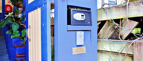 A blue security gate with a keypad and a sign that reads "NIGHT BELL PLEASE PRESS AND WAIT."