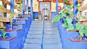 A staircase with blue walls and wooden railings, leading to a door with a sign above it. - Brisbane Manor Hotel (Fortitude Valley)