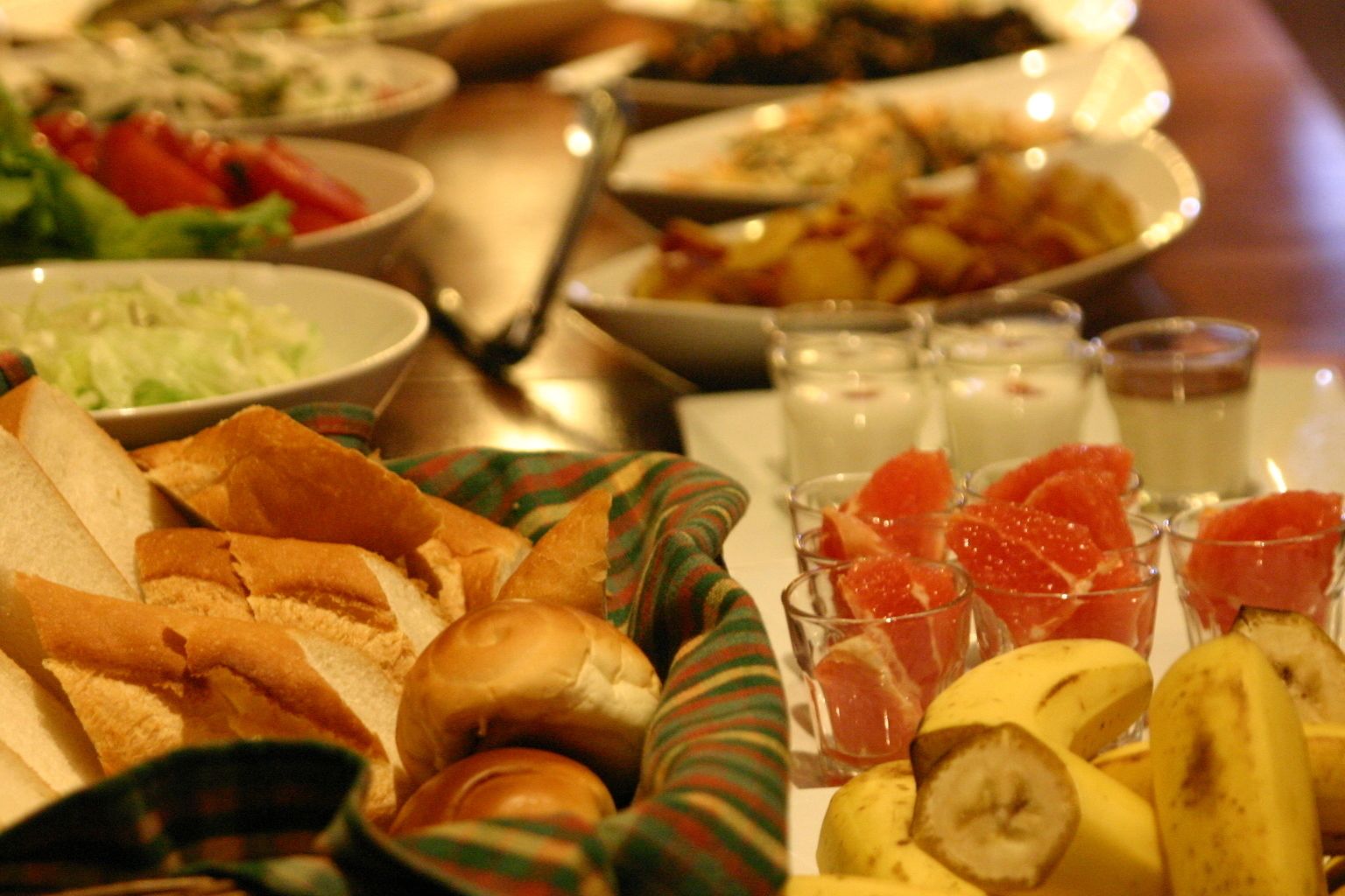 Et bord med forskellig mad, herunder brød, bananer og citrusfrugter.