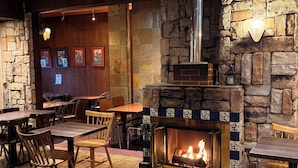 A cozy restaurant with stone walls, wooden tables, and a fireplace. - Hotel Gasthof (Kagoshima)