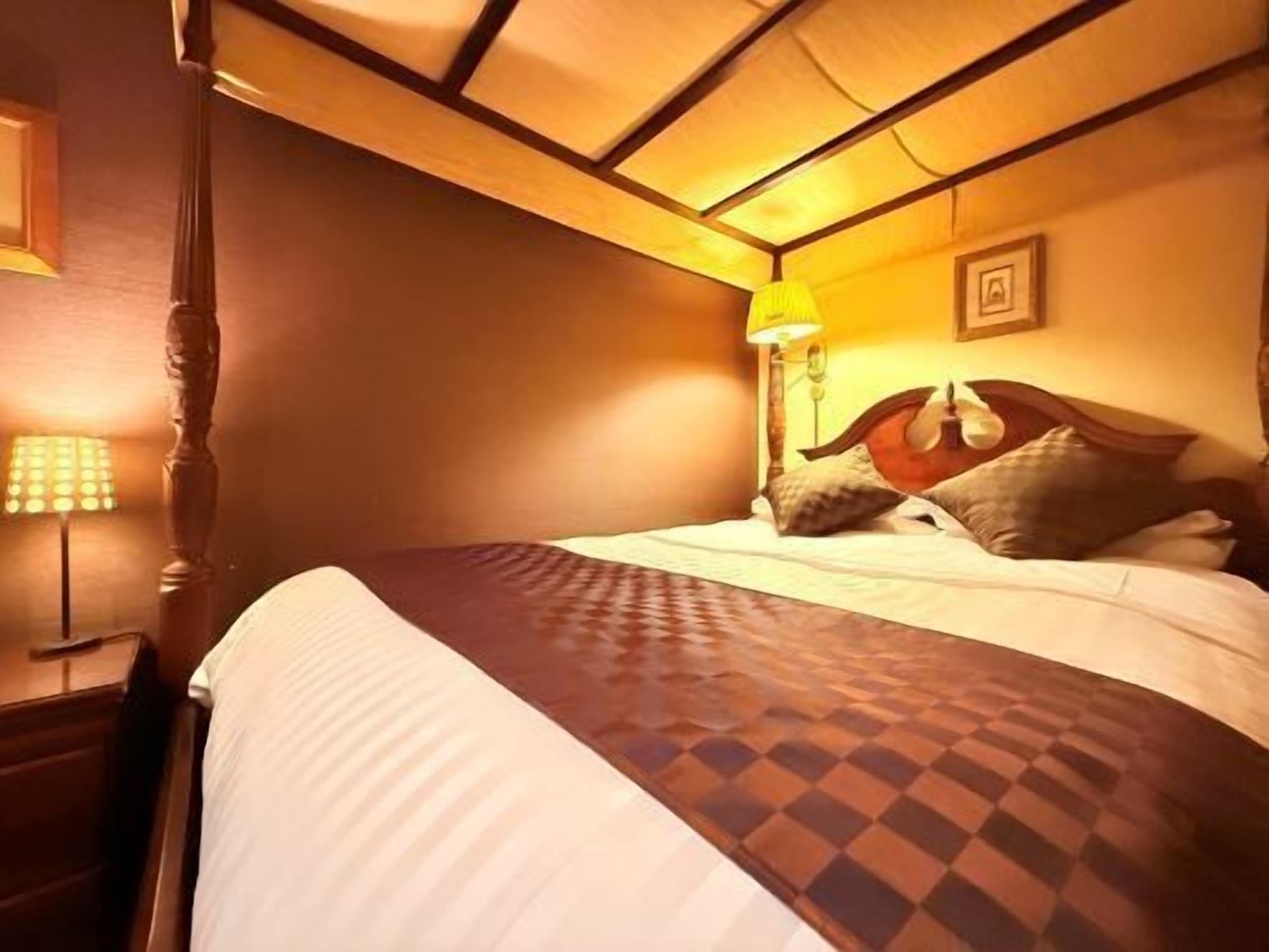 A hotel room with a bed, a nightstand, a lamp, and a picture on the wall.