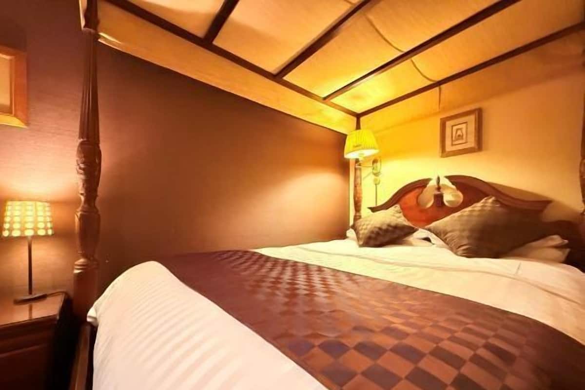 A hotel room with a bed, a nightstand, a lamp, and a picture on the wall.