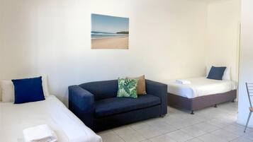 A hotel room with two beds, a sofa, and a wall-mounted picture.