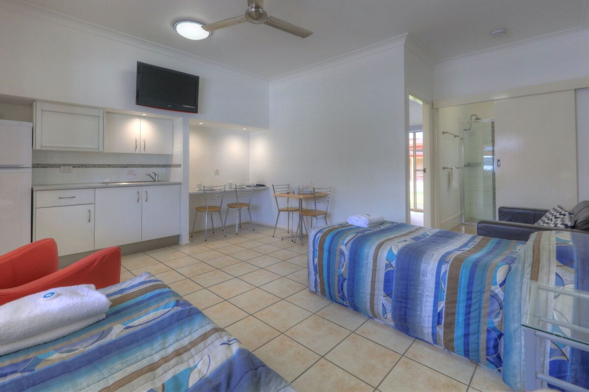 A room with a bed, a desk, a chair, a shower, and a TV.
