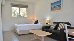 A bedroom with a bed, bedside table, and a window.