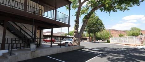 A building with a balcony, a parking lot, and a tree.