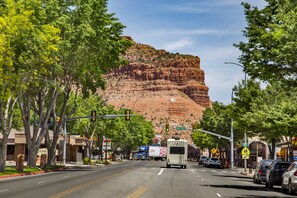 A street view with a prominent red rock formation in the background, a hotel sign, and a traffic light. - Aiken's Lodge (Kanab)