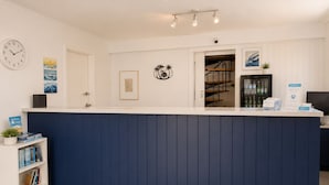A reception desk with a clock, framed artwork, and a welcome sign. - Forster Motor Inn (Forster)