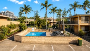 A pool area with a sign indicating it's for guests only, surrounded by palm trees and a brick wall. - Forster Motor Inn (Forster)