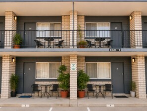A two-story building with numbered doors, outdoor seating, and a sign indicating parking restrictions.