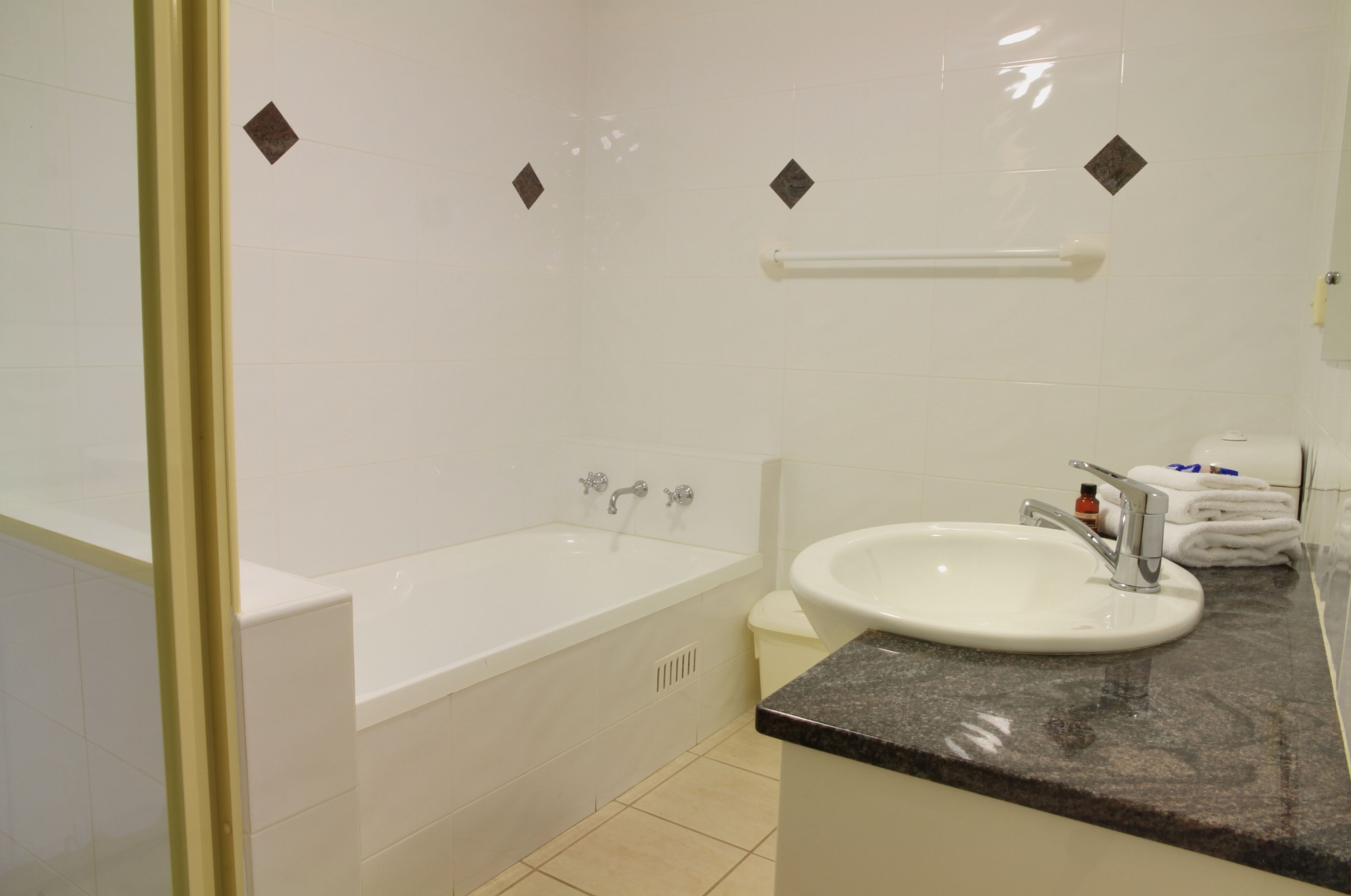 Uma casa de banho moderna com banheira, lavatório e porta-toalhas.