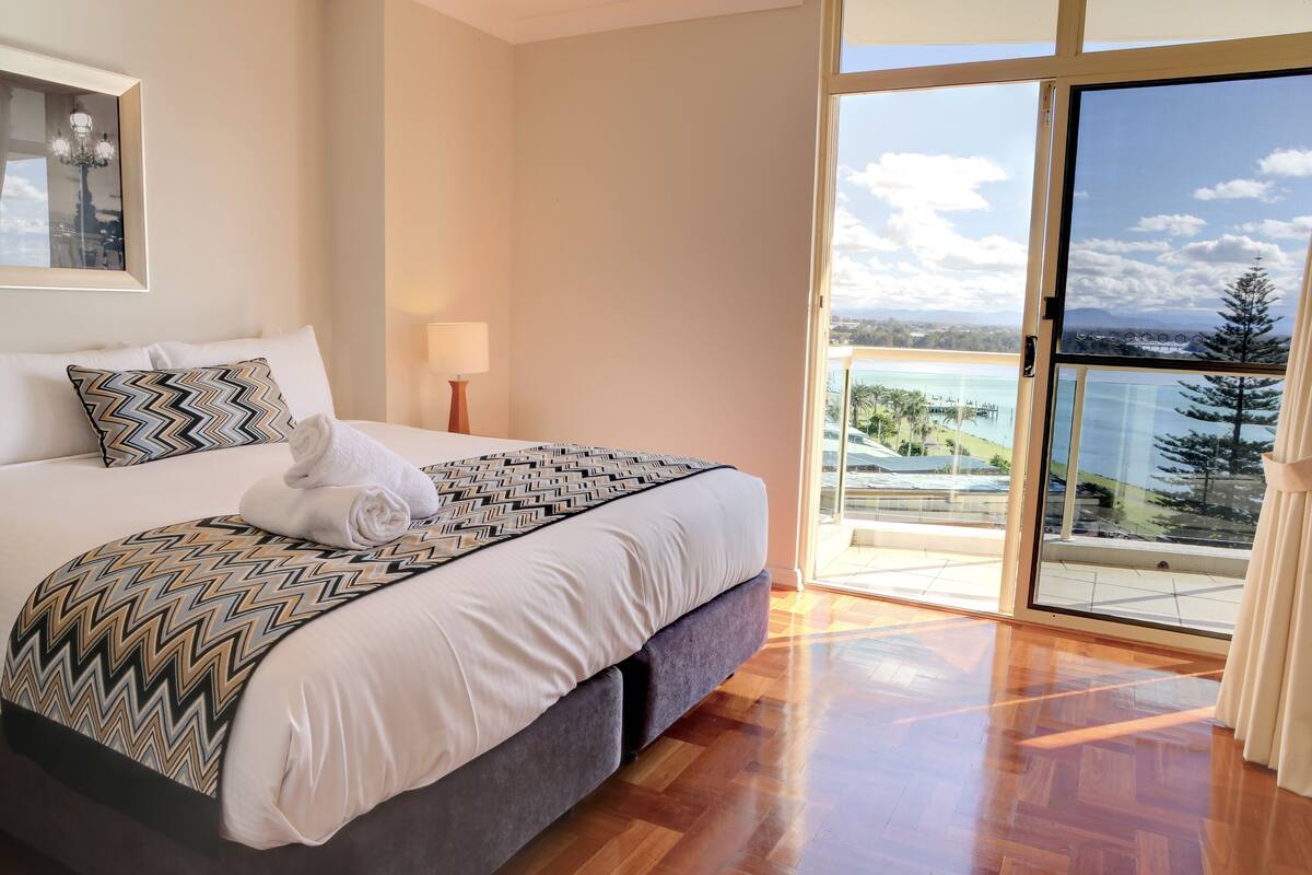 Un dormitorio con una cama grande, vistas al exterior y un balcón.