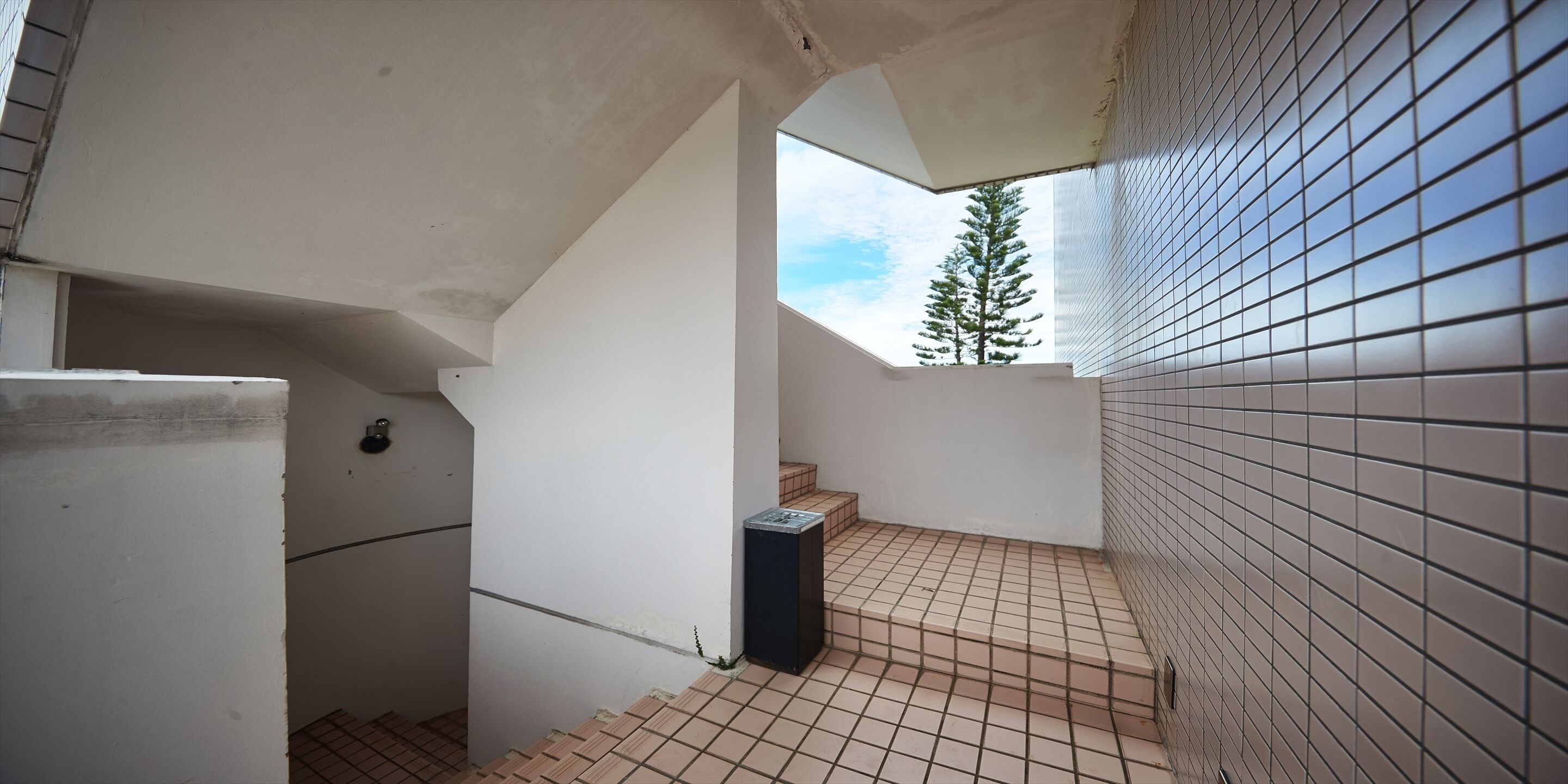 Un pasillo estrecho con suelo de baldosas, una pared blanca y otra pared de cerámica.