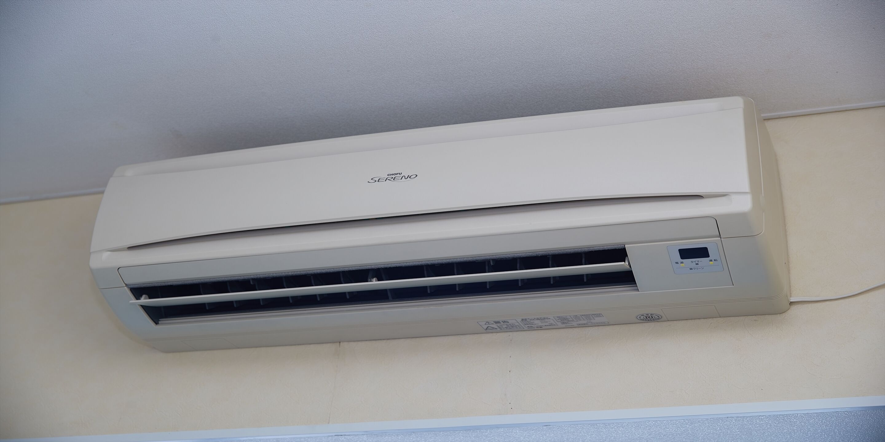 A wall-mounted air conditioner with a control panel and a brand name label.
