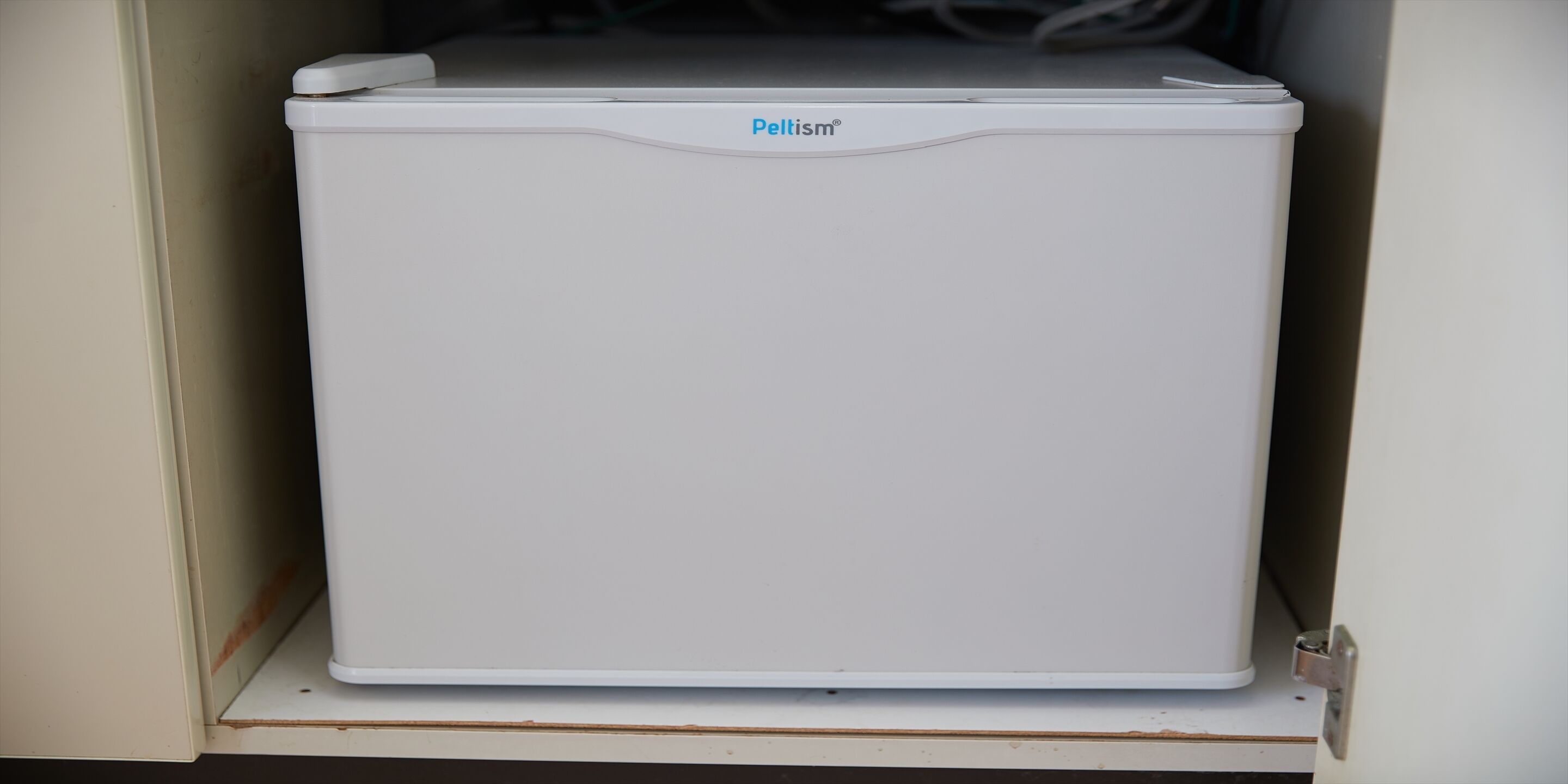 Een witte Pelism® koelkast in een keukenkast.