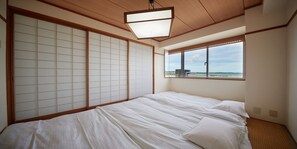 Ein Zimmer mit einem Bett, verschiebbaren Shoji-Bildschirmen, einem Fenster mit Blick und einer Deckenleuchte.