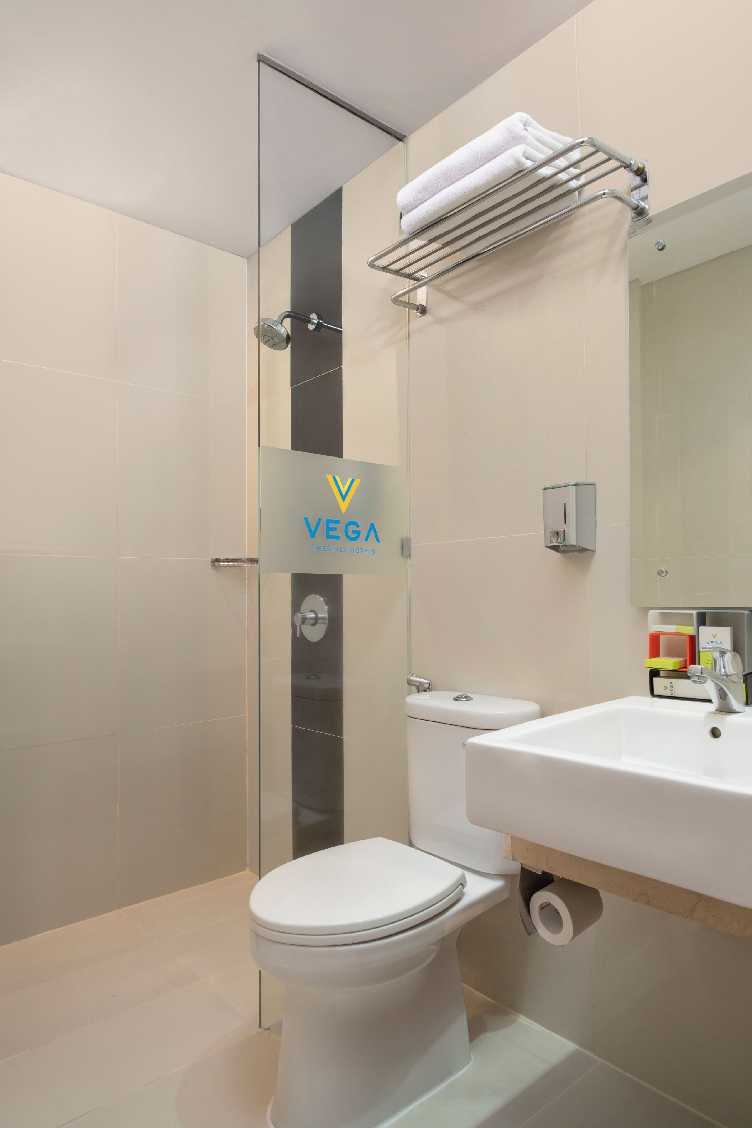 Een moderne badkamer met een douchecabine van glas, een toilet, een wastafel en een handdoekrek.