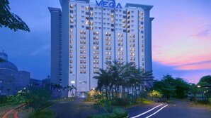 Un hôtel à plusieurs étages, reconnaissable à son grand panneau « VEGA », qui présente une architecture moderne avec un toit plat et une disposition uniforme des fenêtres.