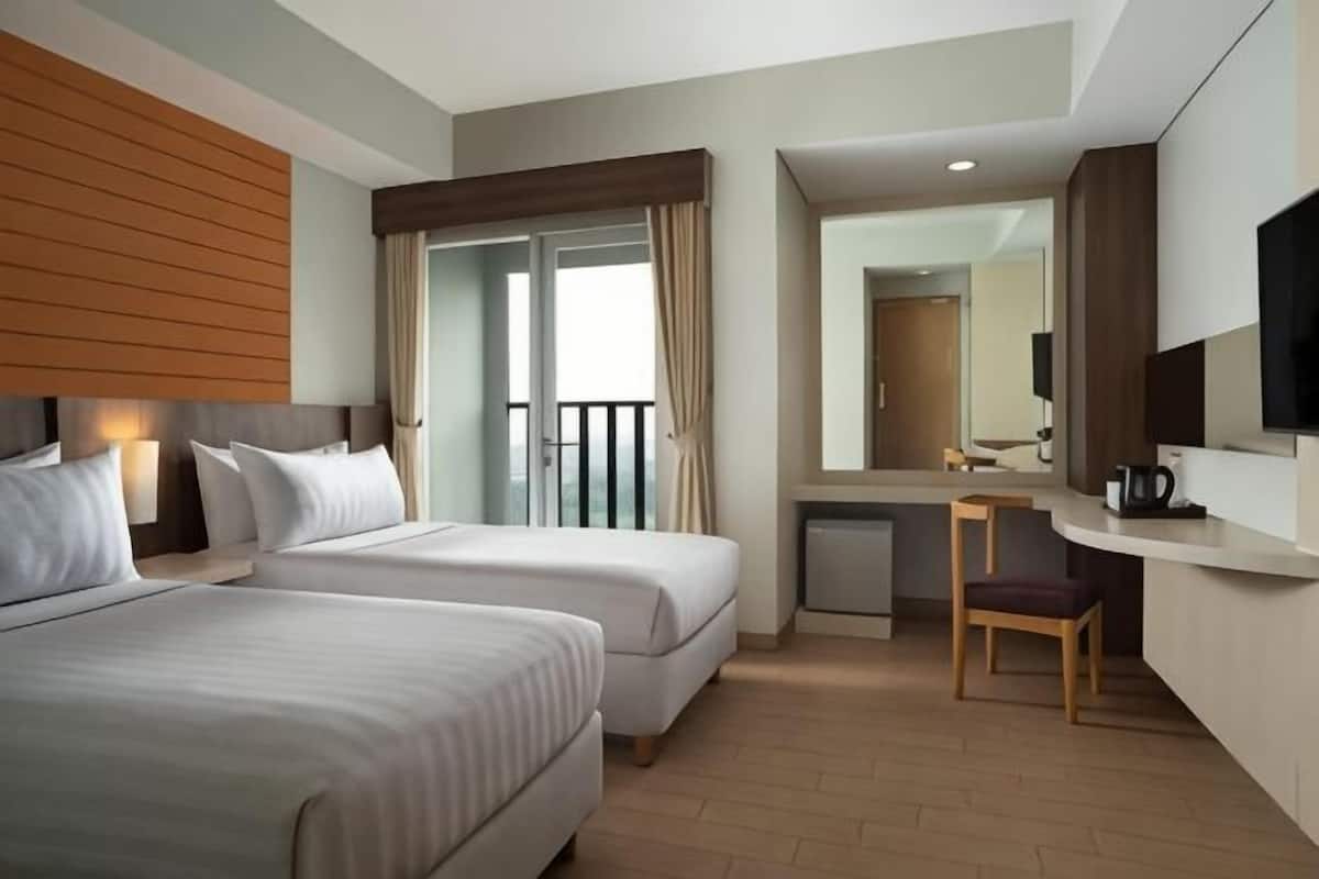 A hotel room with two beds, a desk, a chair, a television, and a balcony.