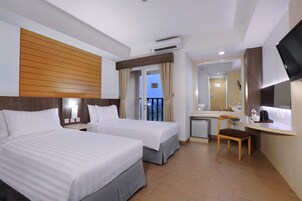 A hotel room with two beds, a desk, a chair, a TV, and a balcony with curtains.