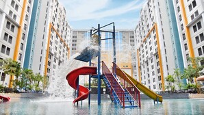 Un parc aquatique avec des toboggans et une fontaine, entouré de gratte-ciel.
