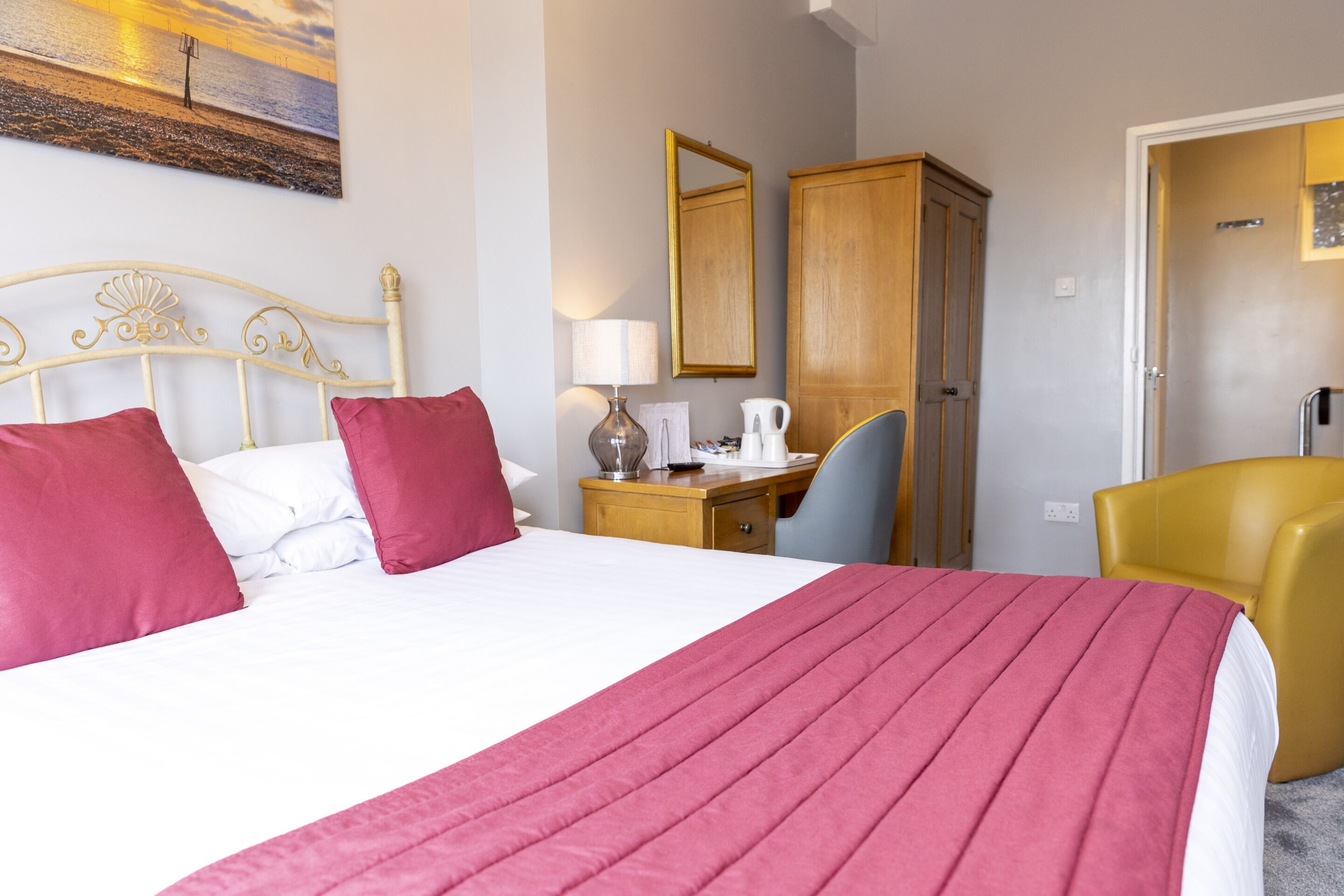 Quarto de hotel com cama, escrivaninha, cadeira e guarda-roupa.