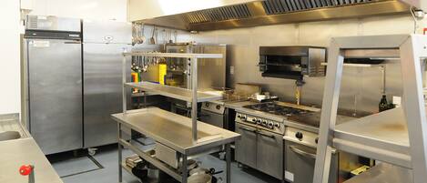 Una cocina comercial equipada con electrodomésticos de acero inoxidable, incluyendo un refrigerador, horno y estufa.