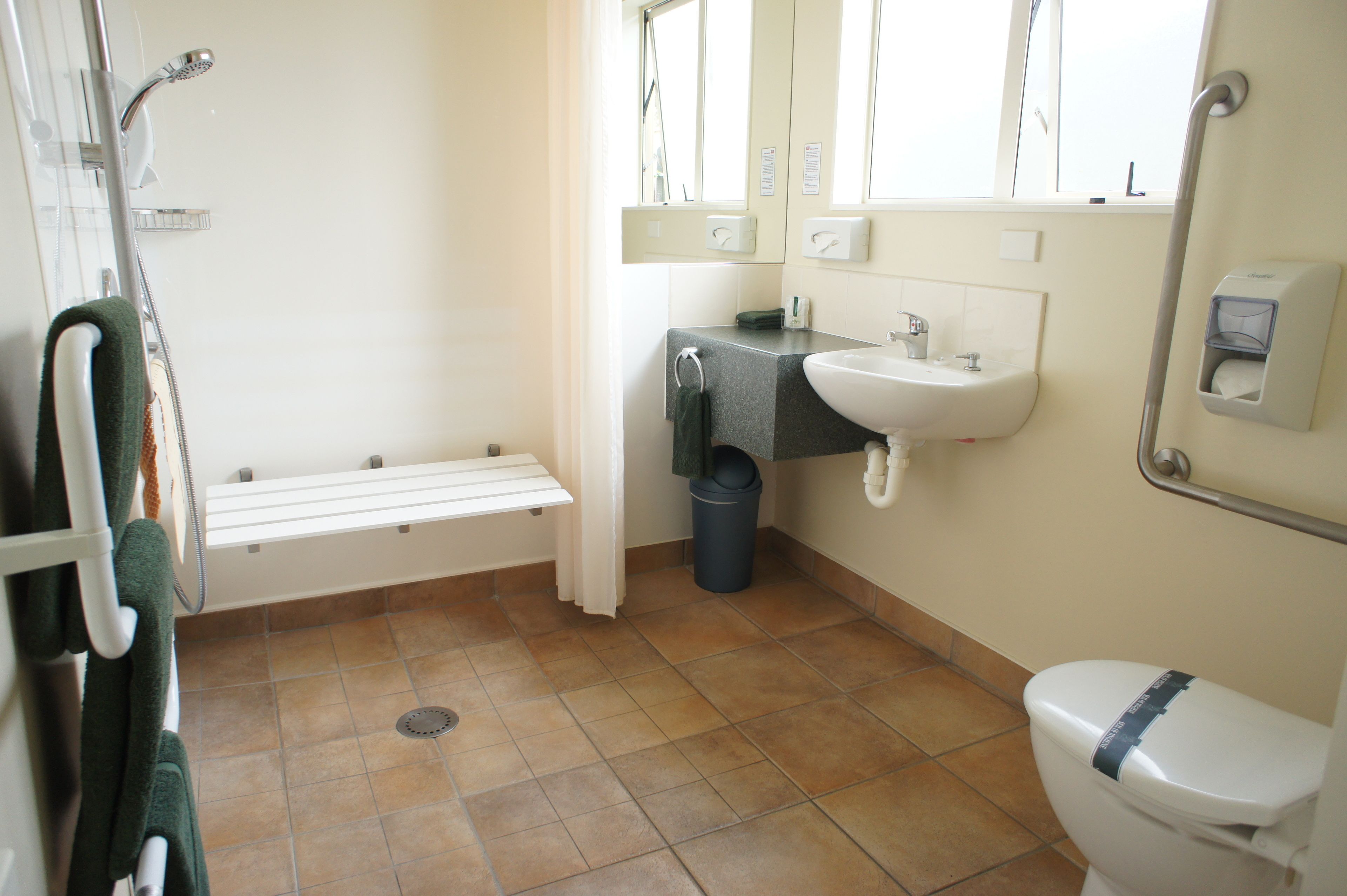 Ein Badezimmer mit Dusche, Waschbecken, Toilette und einem Mülleimer.