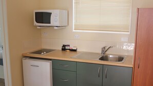 A compact kitchen with a microwave, sink, and a small refrigerator.