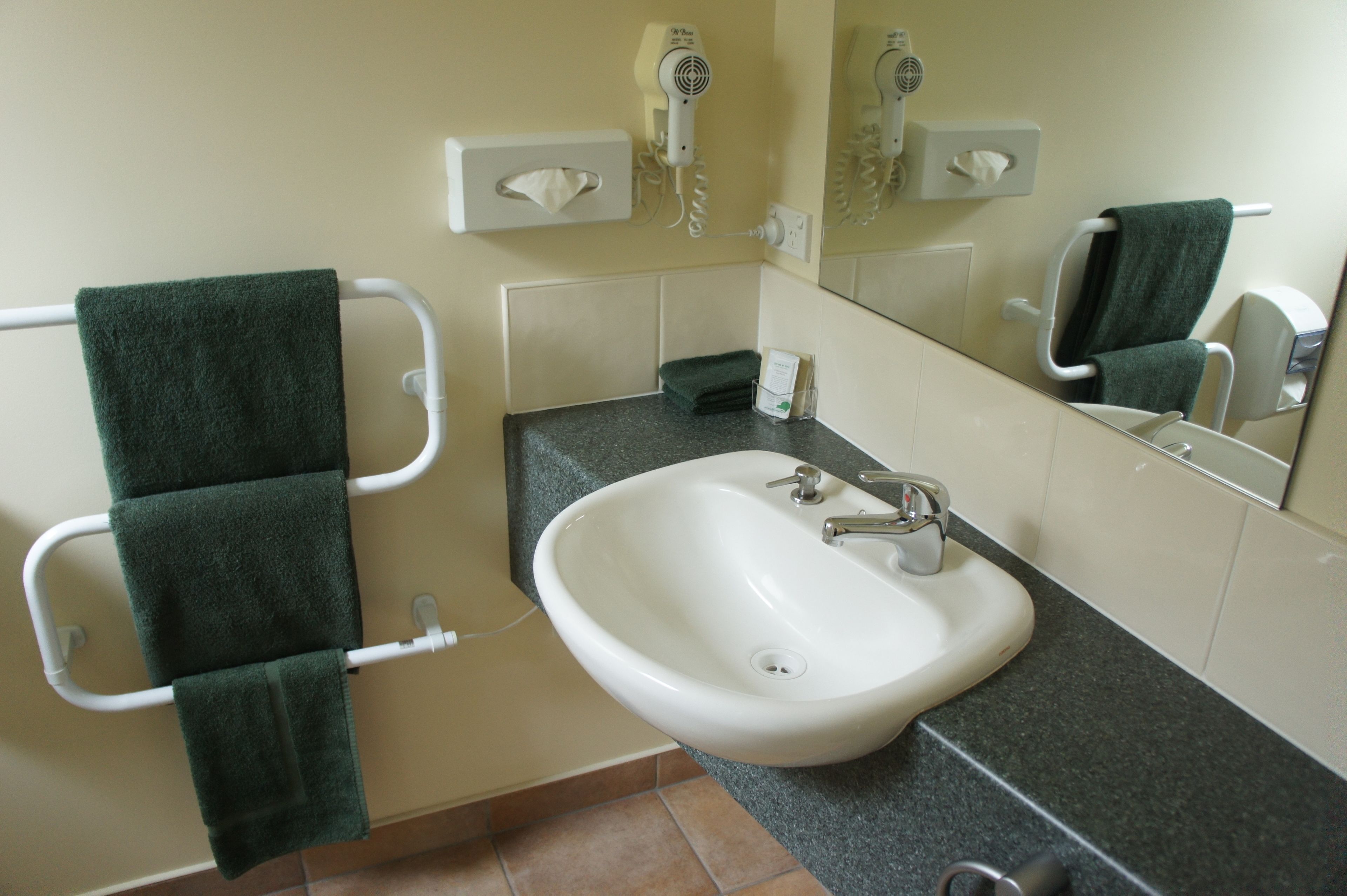 A bathroom with a sink, towel rack, and a hairdryer on the wall.