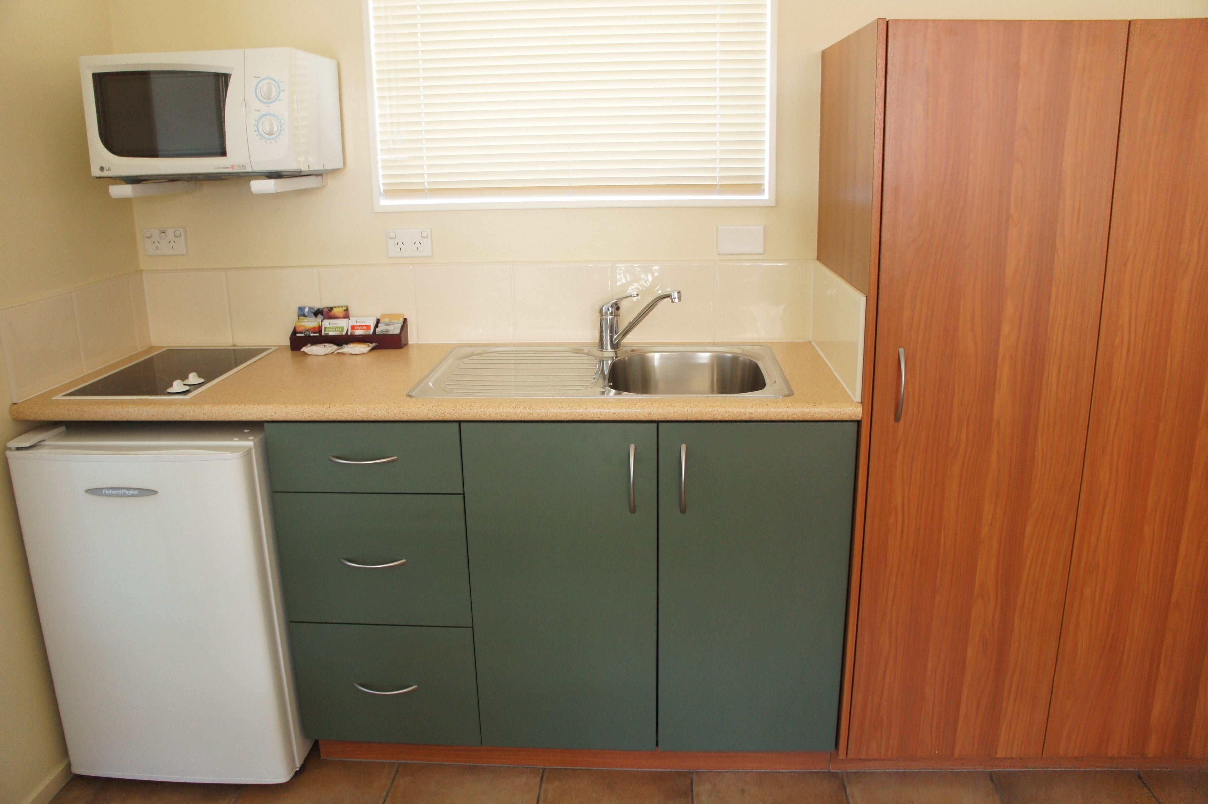 Una cocina compacta equipada con microondas, fregadero y un refrigerador pequeño.