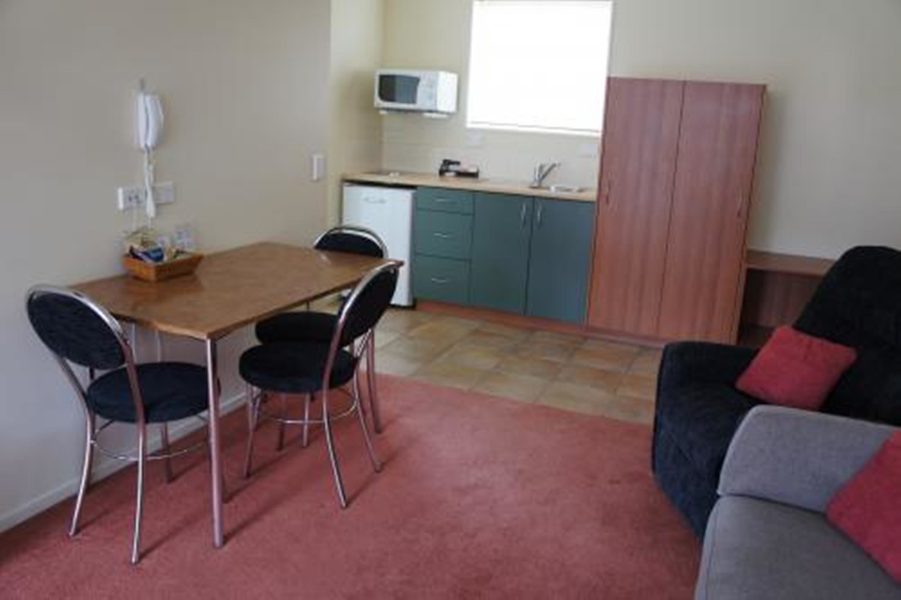 A compact living space with a dining area, kitchenette, and a sofa.