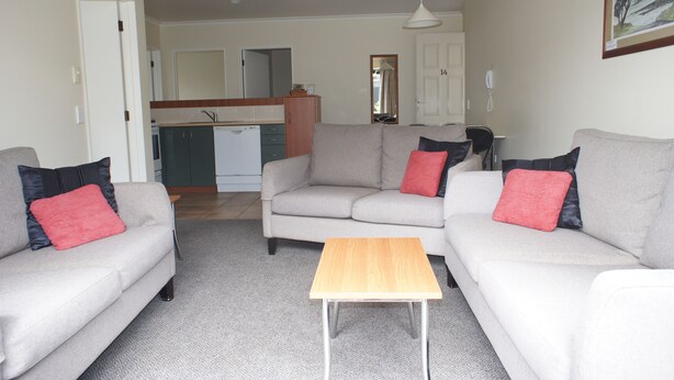 A living room with two sofas, a coffee table, and a kitchen in the background.