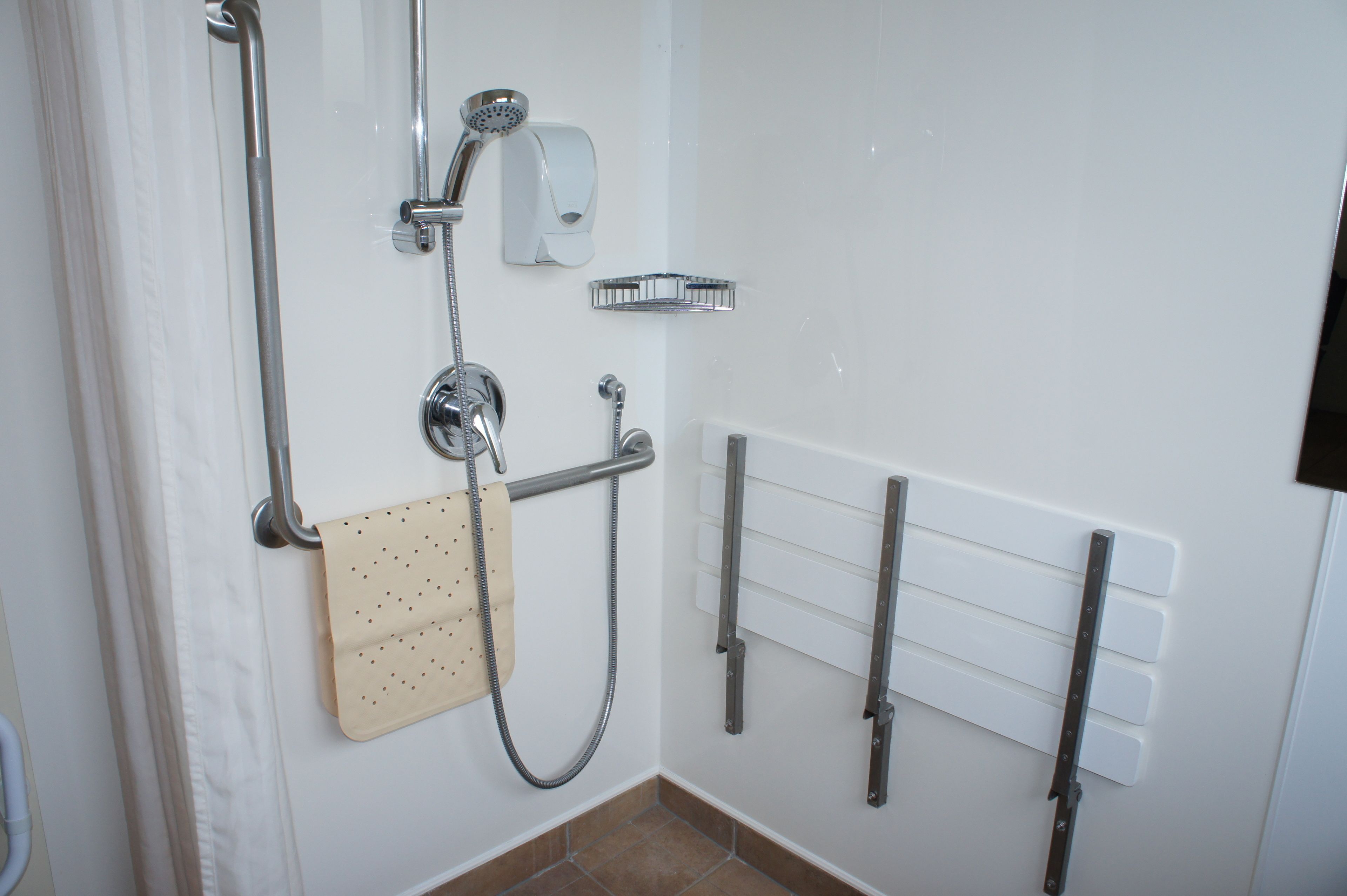 A bathroom with a shower, a towel rack, and a hand dryer.