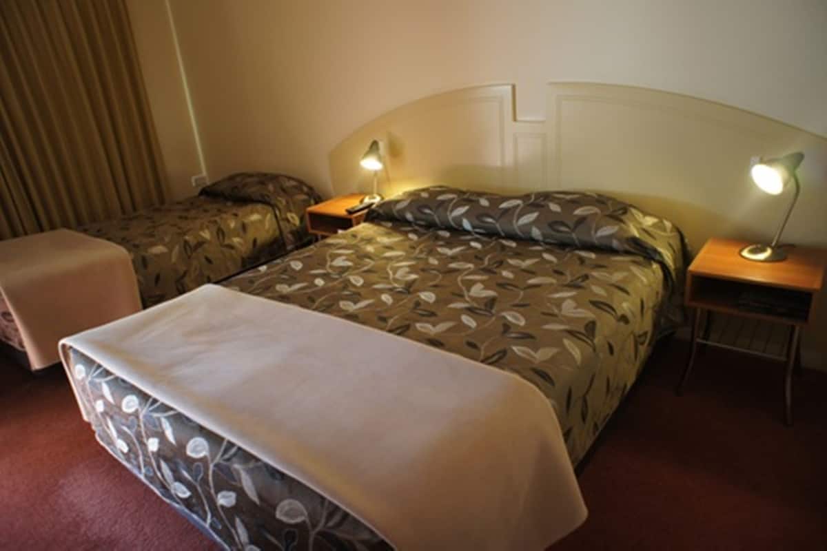Ein Hotelzimmer mit zwei Betten, jeweils mit Kopfstütze und Nachttischlampen.