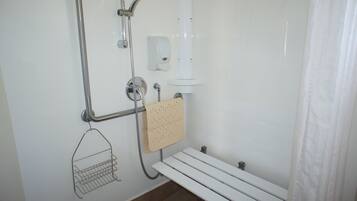Un angolo doccia con soffione a mano, dispenser di sapone a parete e una panca.