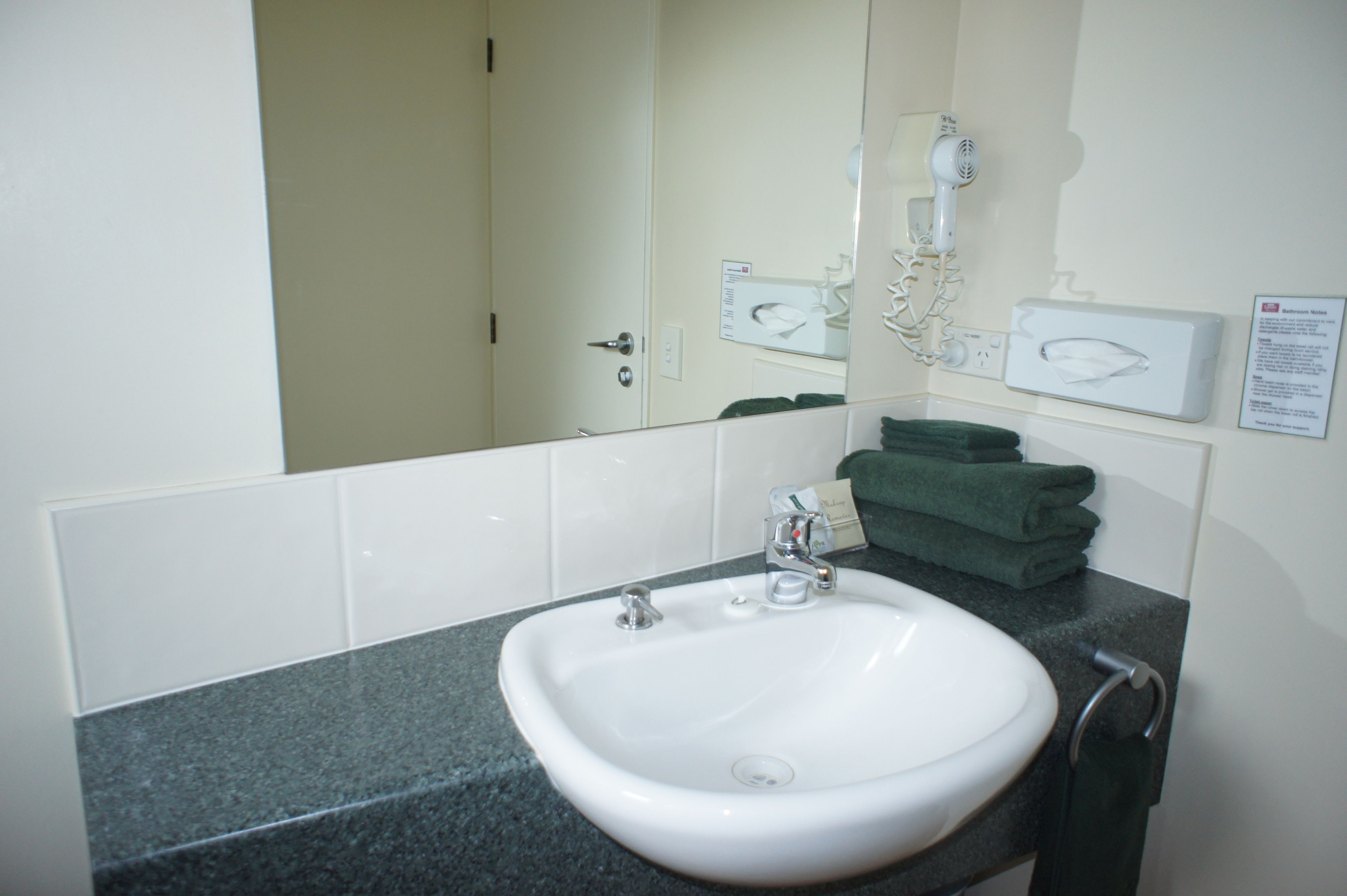 A bathroom with a white sink, a mirror, and a towel rack.
